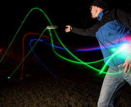 Person beim Werfen einer Leucht-Frisbee bei Nacht